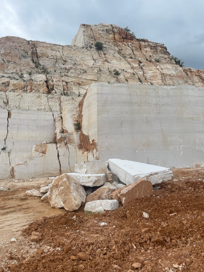 Cracked rock formations and quarried blocks under a cloudy sky.